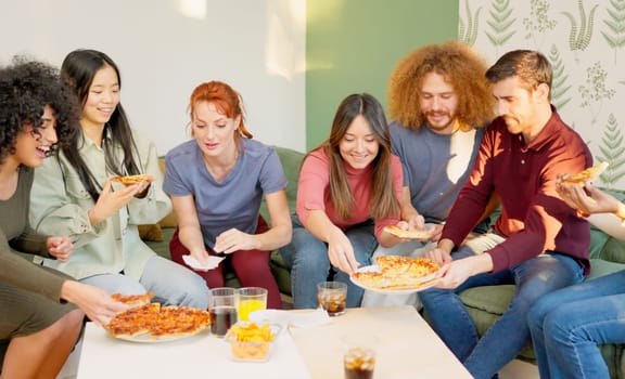 Multi-ethnic friends chilling and smiling eating pizza together at home