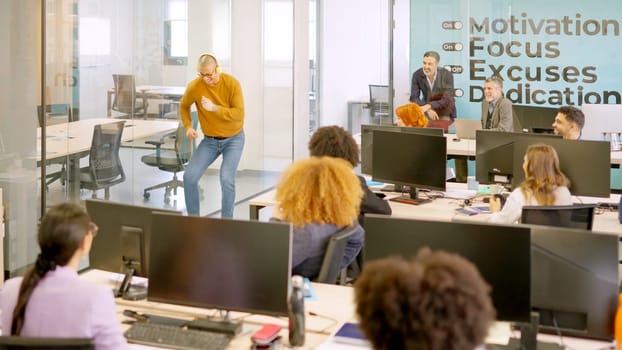 Coworker dancing happily on a corridor in front of colleagues