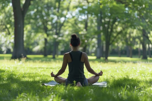 A woman performs a meditative yoga pose in the tranquil surroundings of a lush park, with sunlight filtering through the trees
