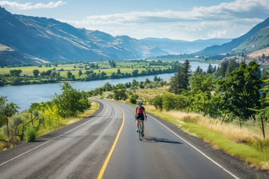 Cyclist riding on a picturesque road alongside a mountainous lake under a clear blue sky