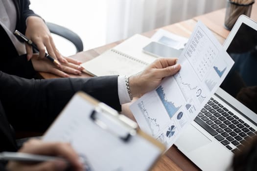 Diverse group of business analyst team analyzing financial data report paper on office table. Chart and graph dashboard by business intelligence analysis for strategic marketing planning Meticulous