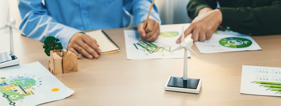 Business people invest in green business plan at meeting room on table with house model and wind mill placed represented eco house and renewable energy. Closeup. Delineation.