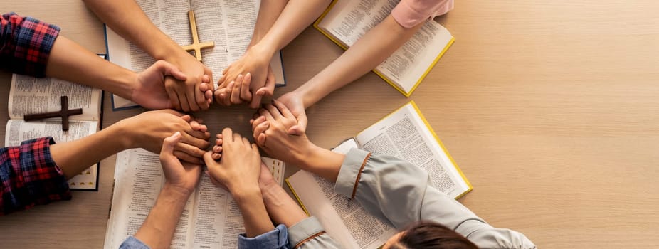 Cropped image of group of people praying together while holding hand on holy bible book at wooden church. Concept of hope, religion, faith, christianity and god blessing. Top view. Burgeoning.