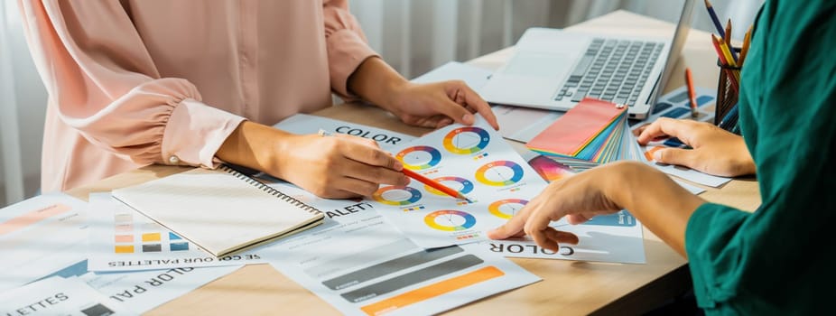 Cropped image of professional interior designers discuss and brainstorm main theme color in project on meeting table with color palette scatter around. Creative interior design concept. Variegated.