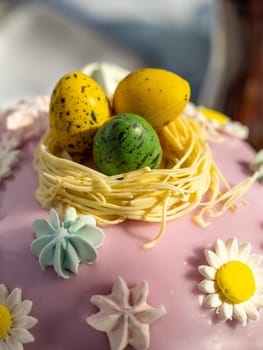 Delicious Easter cake with sugar glaze decorated chocolate eggs and merengue, close up. Festive orthodox easter cake kulich on the table and willow on background