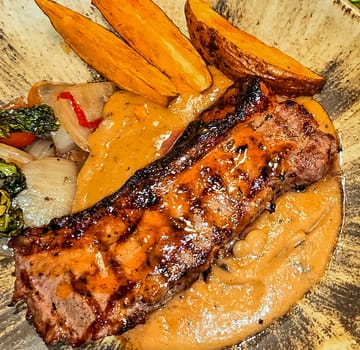 New york strip loin beef steak meat with mushroom sauce and potato wedges and salad plated on beautiful plate on a steak house