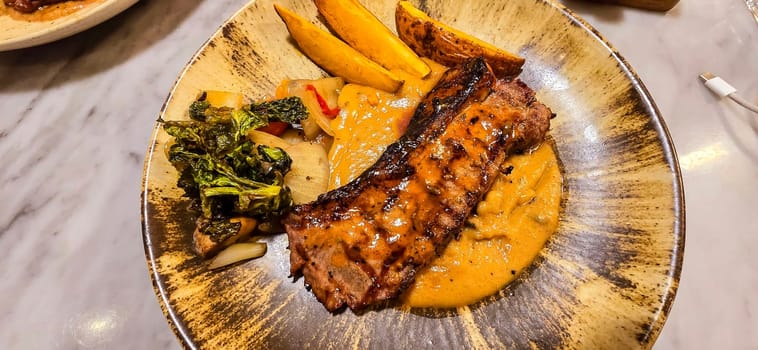 New york strip loin beef steak meat with mushroom sauce and potato wedges and salad plated on beautiful plate on a steak house