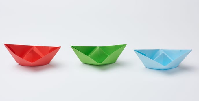 Three paper boats on a white background, close up
