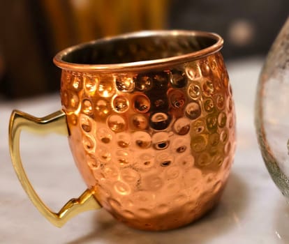 Traditional iced tea served in a unique and artistic brass cup , ice tea garnished with rosemary twigs in a restaurant