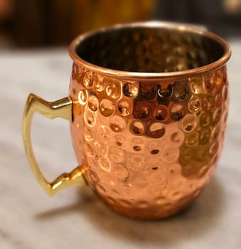 Traditional iced tea served in a unique and artistic brass cup , ice tea garnished with rosemary twigs in a restaurant