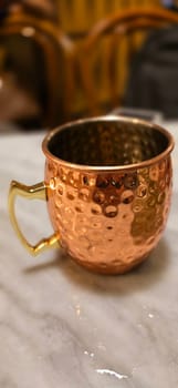 Traditional iced tea served in a unique and artistic brass cup , ice tea garnished with rosemary twigs in a restaurant