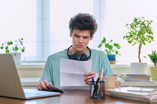 Serious young guy, student of 19-20 years old, reading letter, paper document.