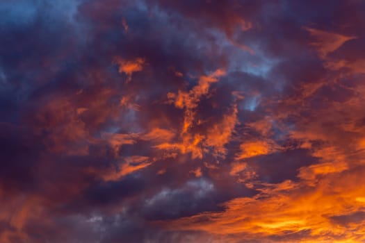 Dramatic fiery bloody sky with orange, red and purple fluffy clouds at sunset