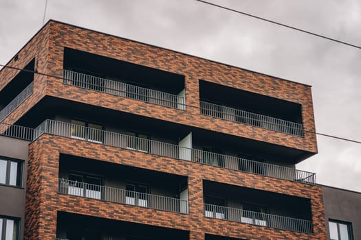 Upper floors of tall residential modern building, contemporary construction facade with brick frames on balcony