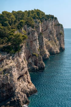 Summer rocks, cliffs with green trees and Adriatic Sea waves, coastal nature of Dugi otok island, Telascica National Park, Croatia