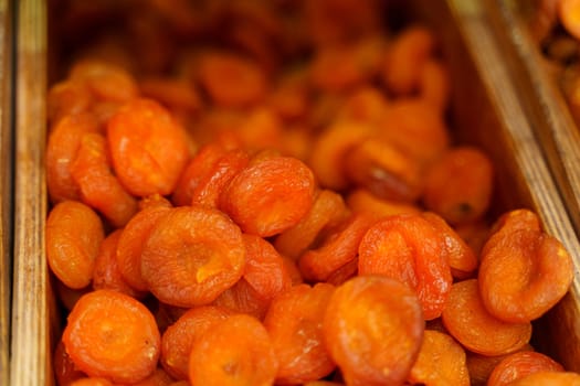 A selection of golden dried apricots showcased for sale, capturing their wrinkled texture and vibrant orange hue.