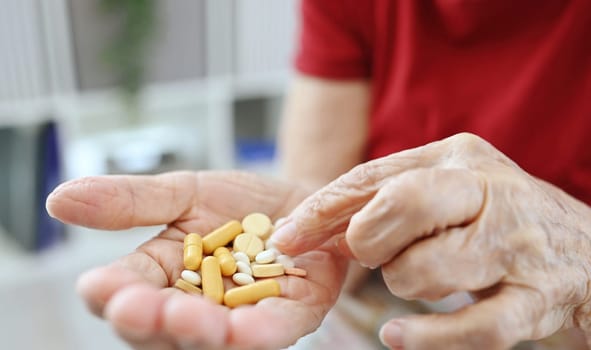 Elderly Woman Counts Pills And Capsules In Her Palm, Medical Drugs And Vitamins For Older People