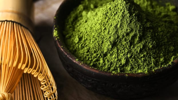 Matcha green tea powder in a bowl with a whisk for whipping