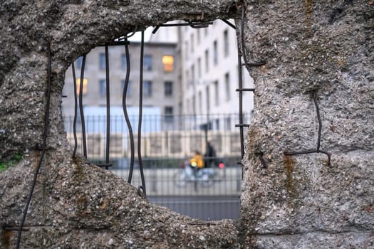 Bicyclists in the hole in Broken Berlin wall between East and west Berlin, symbol of the Cold War. Concept of freedom and independence.