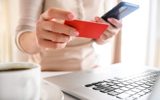 Girl with credit card and laptop shopping online. Woman making purchases in internet and paying with debit using computer
