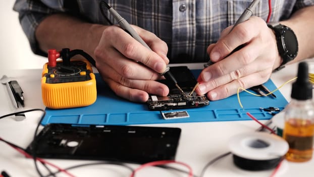 Master Technician In An Electronics Repair Service Center Is Fixing A Smartphone, Disassembling The Phone