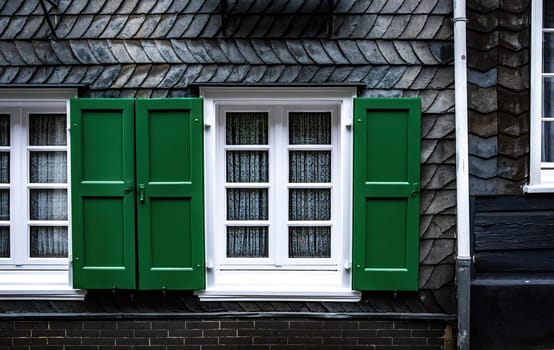 Window with open green shutters, traditional exterior of germany slate house