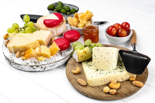 Different kinds of cheese served with green olives, tomato and grape for gourmet nutrition. Organic parmesan and brie with honey delicatessen