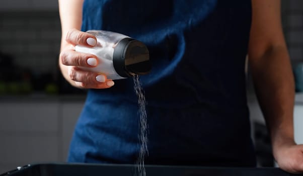 Woman Salting Food With A Salt Shaker At The Kitchen