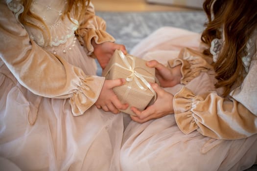 Close-up of a gift box in the hands of two girls. For birthday, Christmas and New Year. Family lifestyle, holiday celebration