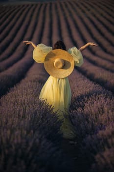 Woman lavender field sunset. Back view woman in yellow dress and hat. Aromatherapy concept, lavender oil, photo session in lavender.