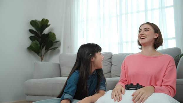 Caucasian smart mom playing game together with daughter for winning or clear game while planning strategy. Attractive mother and daughter spend time together while sitting at living room. Pedagogy.