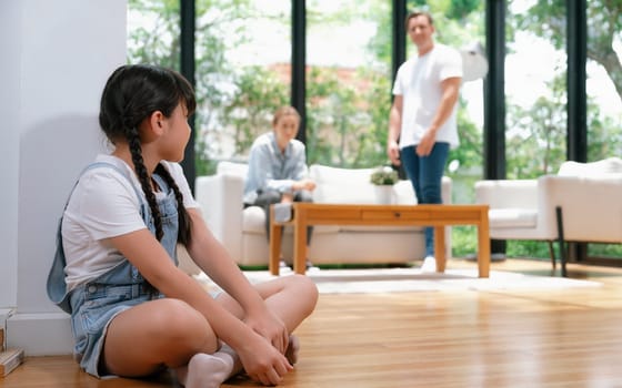 Stressed and unhappy young girl huddle in corner crying and sad while her parent arguing in background. Domestic violence at home and traumatic childhood develop to depression. Synchronos