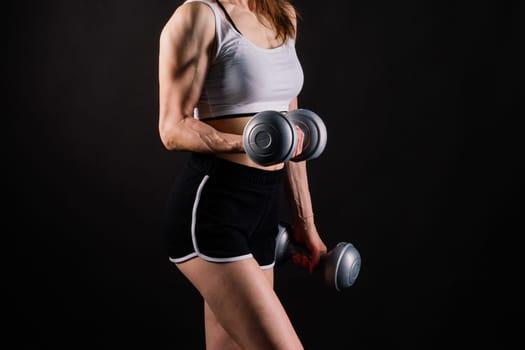 Woman training with a dumbbells, pumping up muscles of hands and legs.