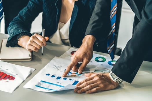 Businessman and businesswoman in meeting working with many financial statement document on desk. Concept of busy business profit analysis and brainstorm. Close up shot at people hands and papers. uds