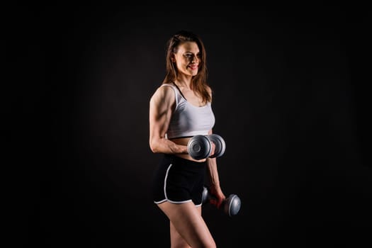 Woman training with a dumbbells, pumping up muscles of hands and legs.