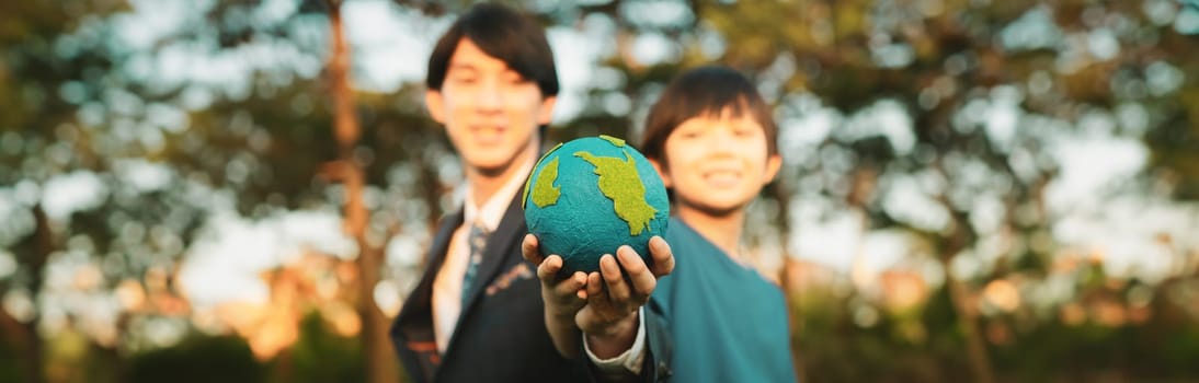 Focus panorama Earth with blur asian boy and businessman holding globe together as Earth day concept. Corporate social responsible to make greener environmental for sustainable future generation. Gyre