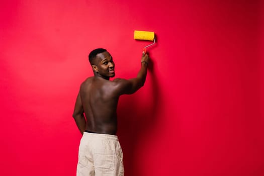 African-American painter on a red studio background topless