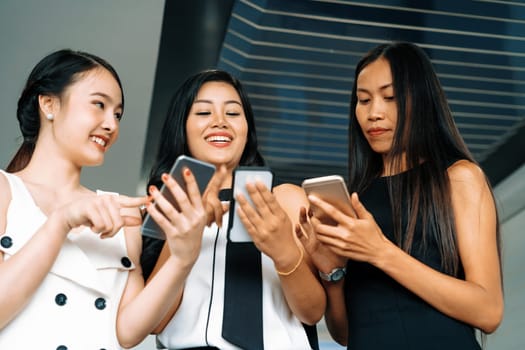 Three women friends having conversation while looking at mobile phone in their hands. Concept of social media, gossip news and online shopping. uds