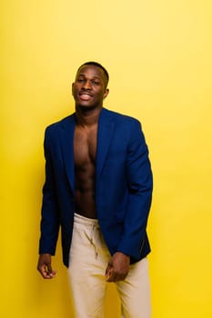 Guy in blue suit on a yellow background. Handsome athletic man in jacket smiling