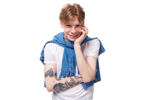 portrait of a young pensive european man with red hair and a tattoo on his arms on a studio background. people lifestyle concept.