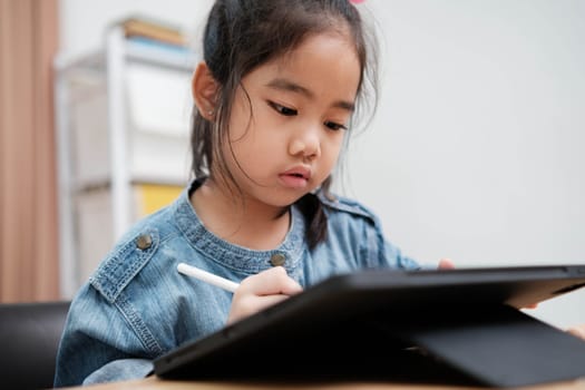 A primary school girl focuses on operating a robotic arm with a remote control, demonstrating STEM education in action.