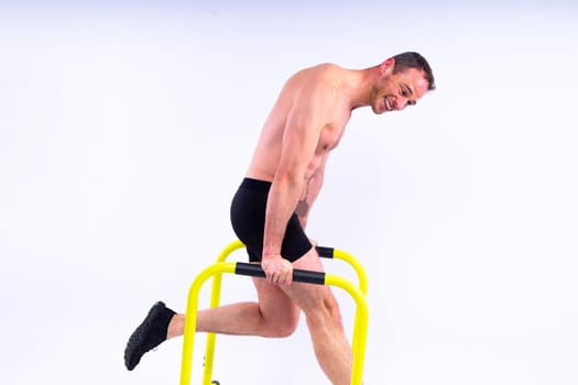 Male gymnast performing handstand on a parallel bars, studio shot