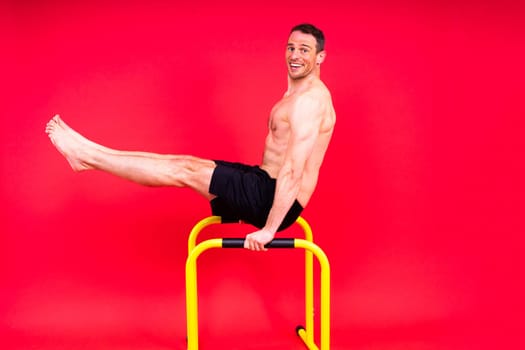 Male gymnast performing handstand on a parallel bars, studio shot