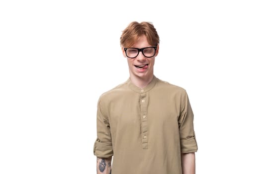 close-up portrait of a stylish european guy with red hair dressed in a fashionable brown shirt and trousers on a white background. people lifestyle concept.