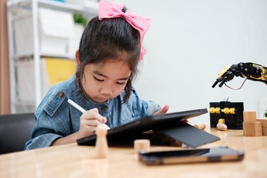 Concentrated young girl in denim using a stylus pen to draw on a digital tablet, embracing technology in education.