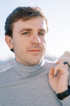 Young man stands with a jacket on his shoulder. Portrait. High quality photo