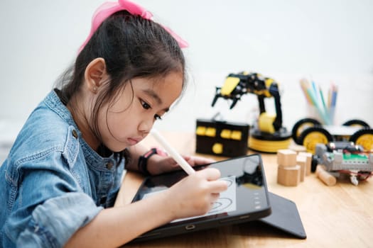 A primary school girl focuses on operating a robotic arm with a remote control, demonstrating STEM education in action.