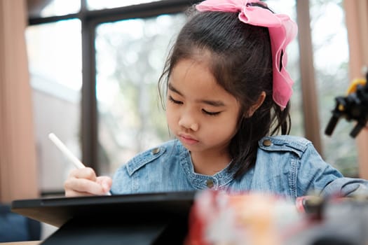 A primary school girl focuses on operating a robotic arm with a remote control, demonstrating STEM education in action.