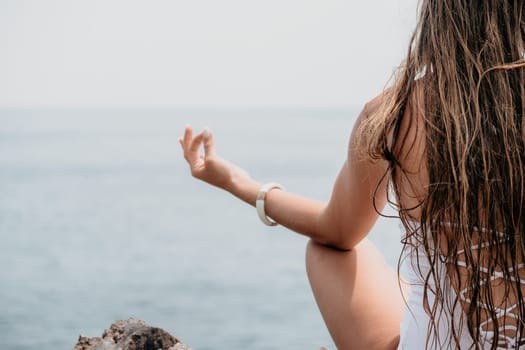 Woman meditating in yoga pose silhouette at the ocean, beach and rock mountains. Motivation and inspirational fit and exercising. Healthy lifestyle outdoors in nature, fitness concept.