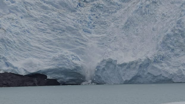 Huge ice pieces fall from glacier, forming splashes and icebergs.